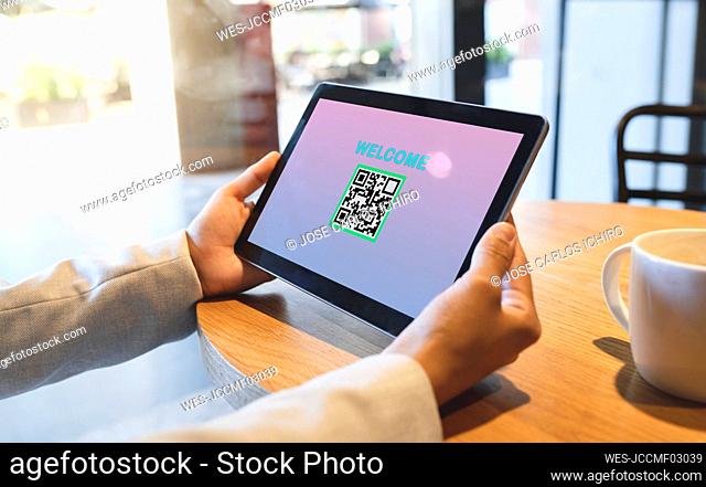 Businesswoman holding digital tablet with QR code and welcome text in coffee shop