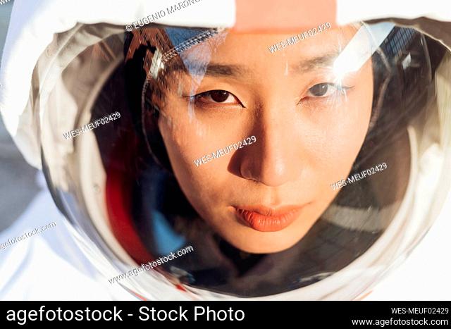 Female astronaut looking up wearing space helmet
