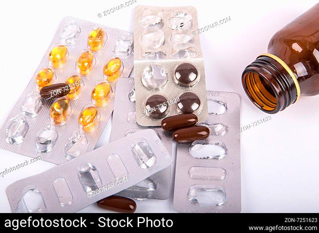 Close-up view of mix of pills and fallen brown glass medical bottle, isolated on white background