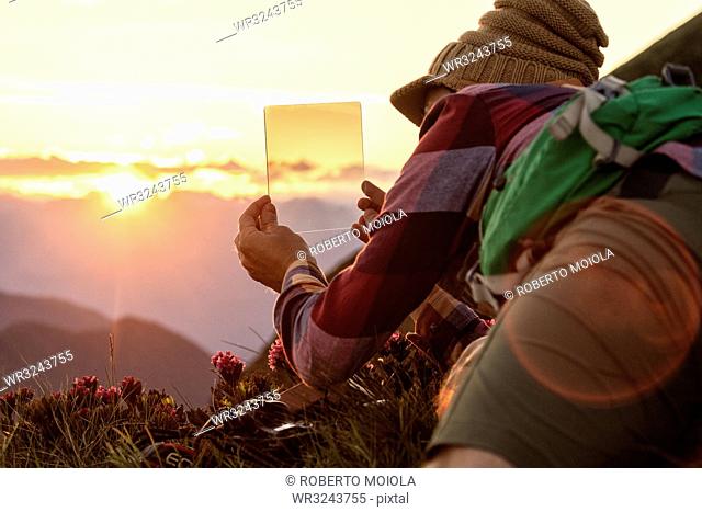 Man at sunset with graduated photography filters in his hand, San Marco Pass, Orobie Alps, Bergamo province, Lombardy, Italy, Europe