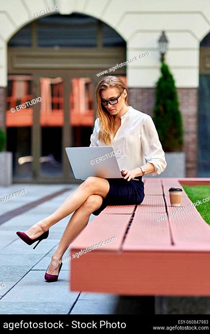 successful business woman in glasses working at laptop outdoors. woman enjoy her work