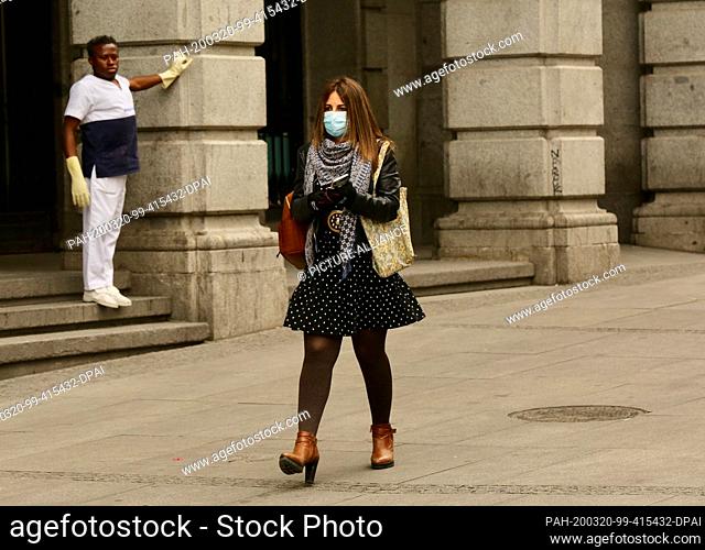 20 March 2020, Spain, Madrid: A woman wearing a mouthguard walks across the Plaza del Sol during a curfew imposed because of the coronavirus