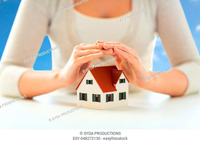 close up of woman protecting house model by hands