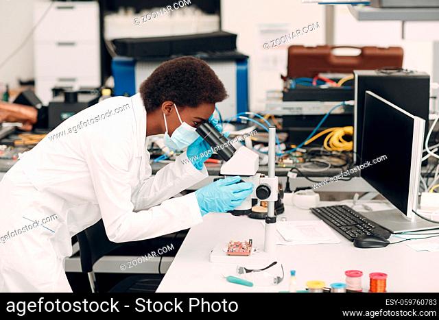 Scientist african american woman engineer working in laboratory with electronic tech instruments and microscope. Research and development of electronic devices...