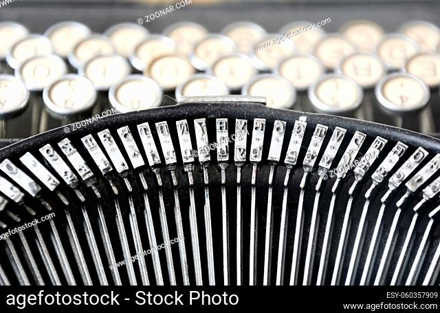 the iron hammers of an old typewriter with the keys blurred in the background. Typing and obsolete technology. Vintage object