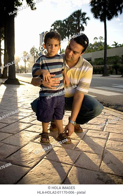 Mid adult man adjusting his son's sandals