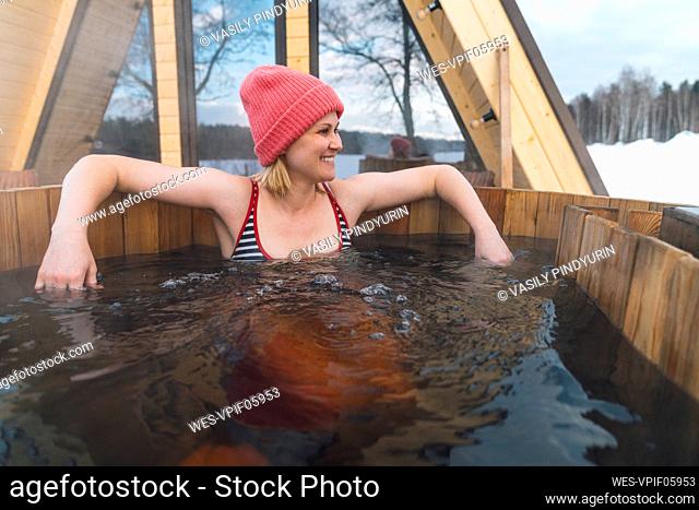 Smiling woman taking bath in hot tub outside house