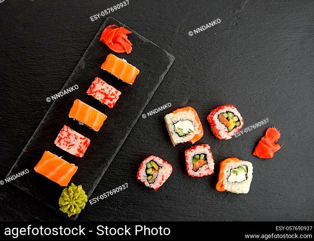 california sushi with red tobiko caviar and slices of philadelphia sushi on black slate board, top view