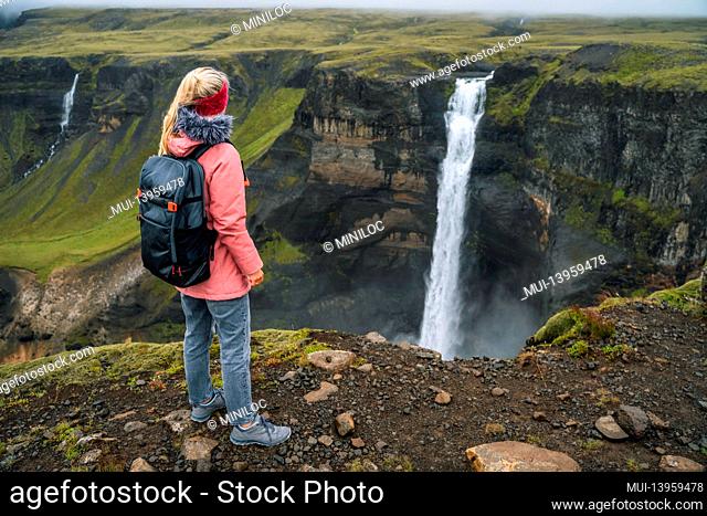 Woman with backpack enjoying Haifoss waterfall of Iceland Highlands