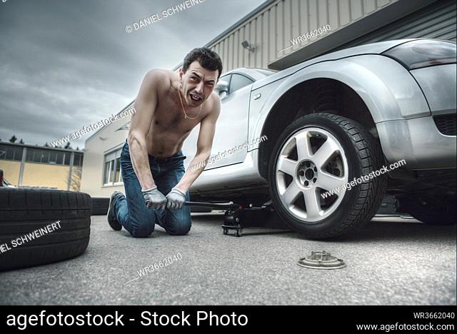 Germany, Bavaria, Kaufbeuren, Mature man changing car tire