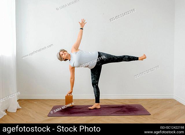 Woman performing Ardha Chandrasana on yoga mat at home