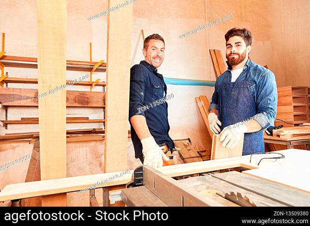 Zwei junge Männer als Schreiner Lehrlinge arbeiten zusammen in der Schreinerei