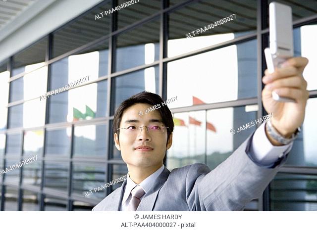 Businessman taking photo with cell phone