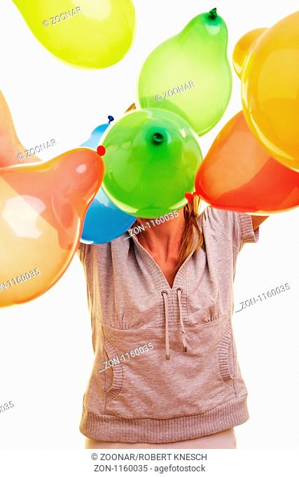 Junge blonde Frau wirft viele bunte Luftballons