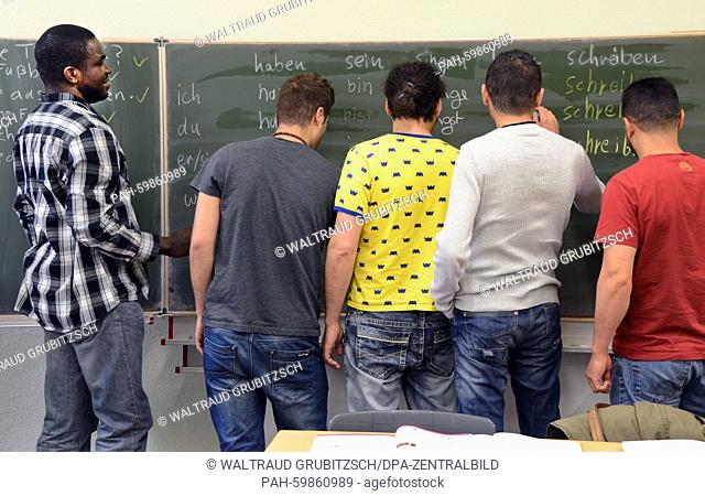 Students from Tunesia, Tanzania, Eritrea and Marocco revise texts on a blackboard in a German-language class at the community college in Leipzig, Germany