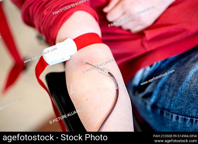 PRODUCTION - 06 May 2021, Lower Saxony, Emstek: Blood runs from a donor's arm through a needle into a bag during a blood donation at the NSTOB blood donation...