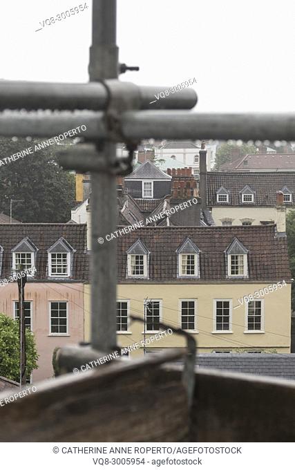 Metal scaffolding poles after the rain, looking out over the historic rooftops and chimneys of Hotwells, Bristol, England