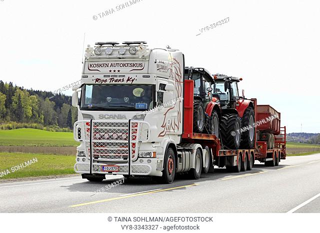 Salo, Finland. May 10, 2019. White customized Scania semi trailer of Ripe Trans Ky hauls two Massey-Ferguson tractors and agricultural trailer on road