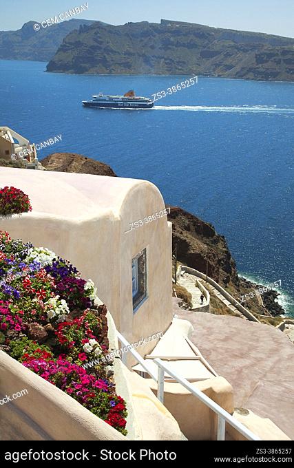 Traditional Cycladic houses at the cliff in Oia village with a ferry near Caldera at the background, Santorini Island, Cyclades Islands, Greek Islands, Greece