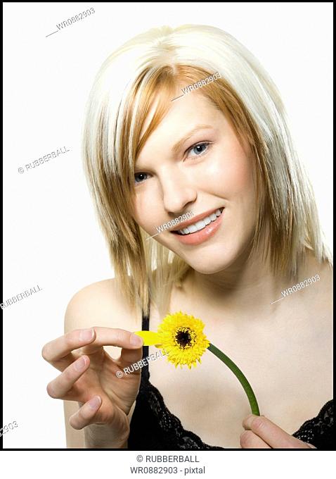 Portrait of a young woman plucking a petal off a flower