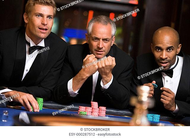 Three men in casino playing roulette selective focus