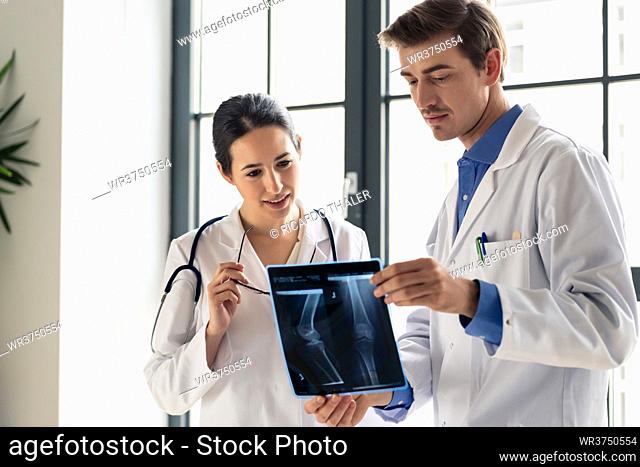 Two young dedicated doctors analyzing together the radiograph of the leg of a patient in a modern hospital
