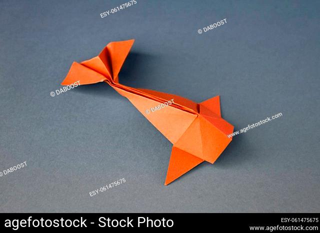 Orange paper fish origami isolated on a blank grey background