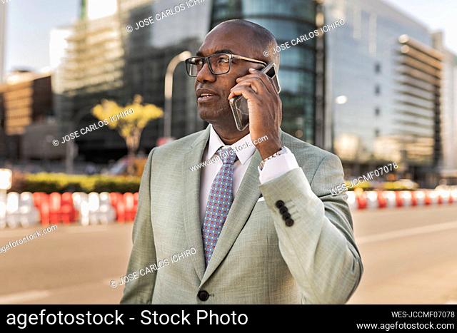 Businessman talking through mobile phone on street at financial district