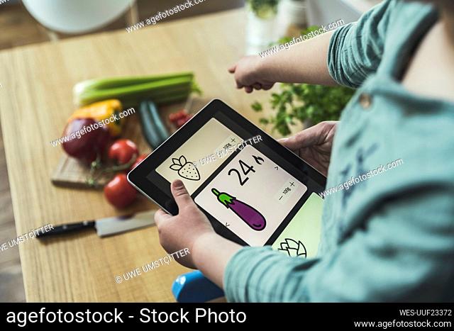 Boy holding digital tablet pointing at vegetables