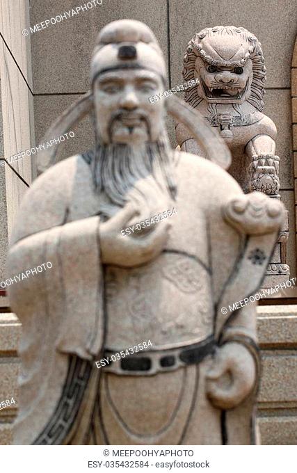 Statues of Chinese deity in focus lion sculpture of chinese temple