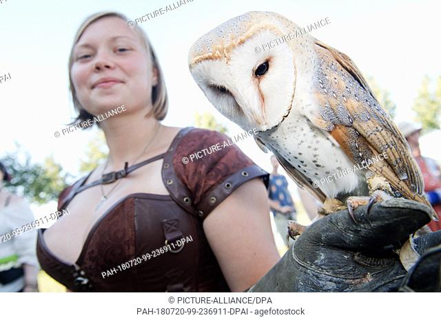 20 July 2018, Germany, Stralsund: Julia Zienicke from the zoo in Stralsund shows a barn owl. Farm hands, dealers, jesters and jugglers during the parade of the...
