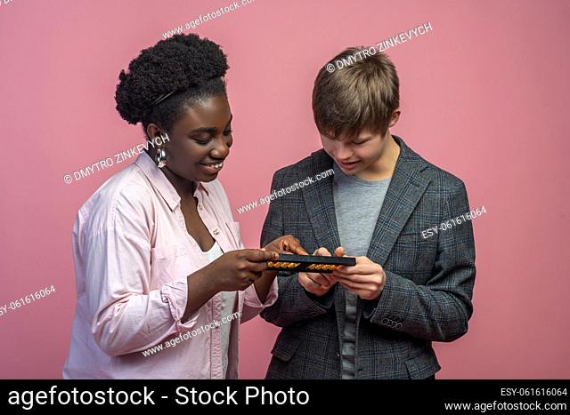 Learning, count. Dark-skinned smiling woman teaching caucasian guy with down syndrome counting on abacus standing on light background