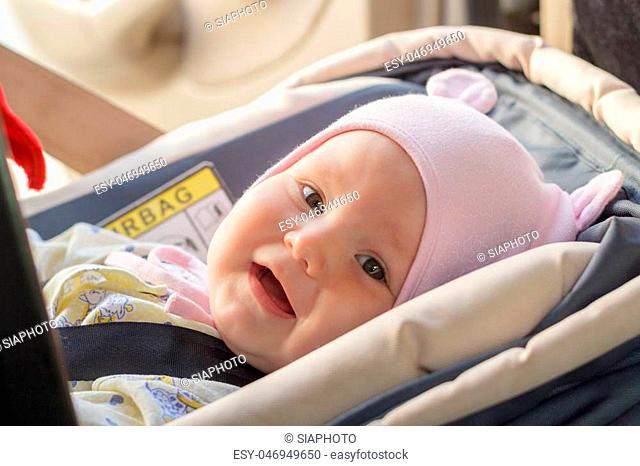 little newborn baby girl rests in the car seat in car
