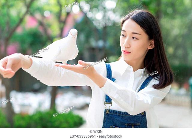 happy laughing girl feeding pigeon sitting on hand
