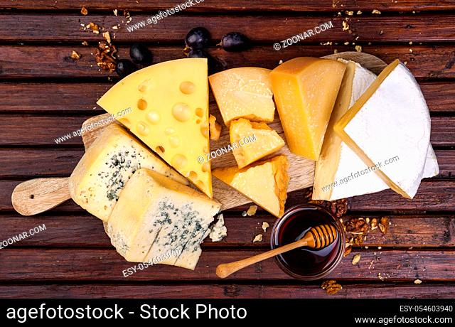 Various types of cheese on wooden table background. Cheddar, parmesan, emmental, blu cheese. Top view, copy space