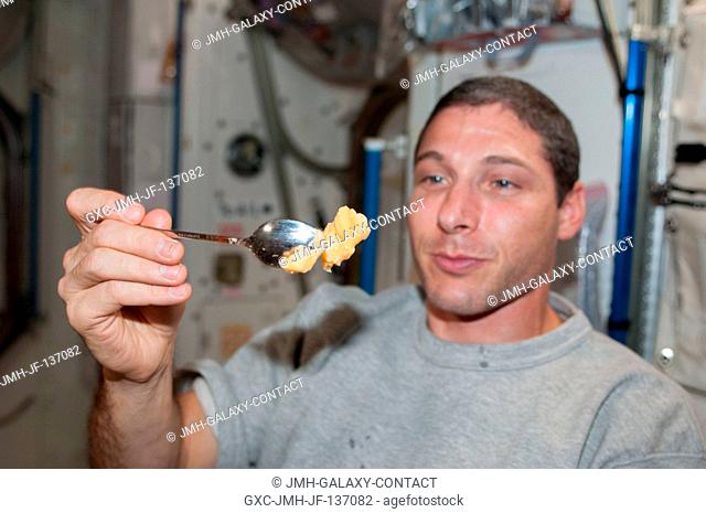 NASA astronaut Michael Hopkins, Expedition 37 flight engineer, holds a spoon containing a piece of food in the Harmony node of the International Space Station
