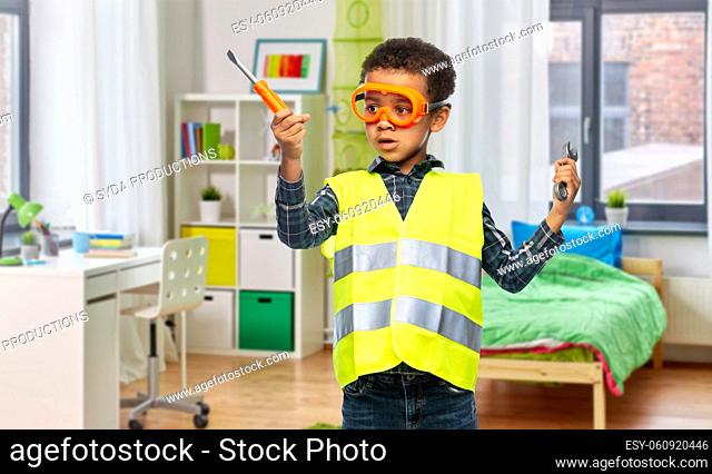 little boy in safety vest with screwdriver at home