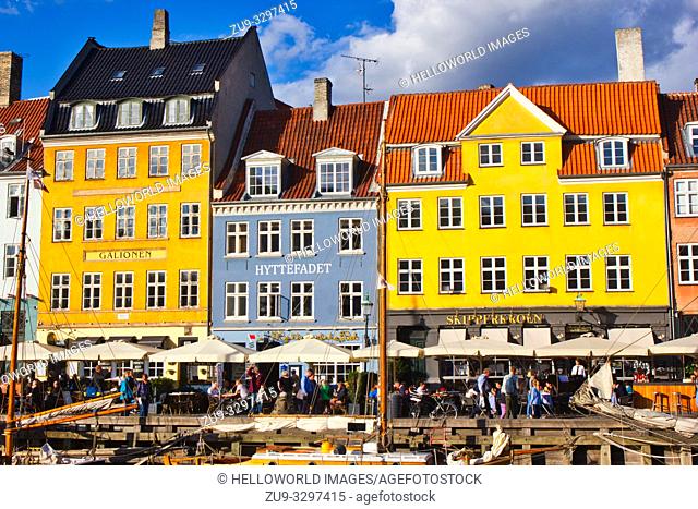 Alfresco canalside tables and chairs and brightly painted townhouses, Nyhavn, Copenhagen, Denmark, Scandinavia. 17th century waterfront canal and entertainment...