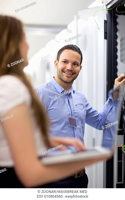 Technician smiling at colleauge holding laptop