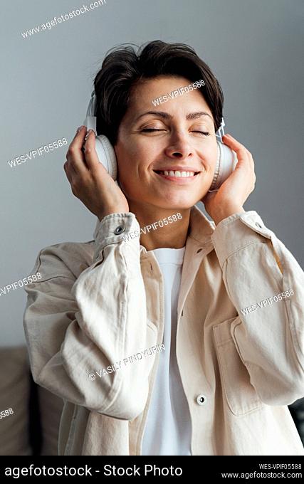 Smiling woman with eyes closed listening music with headphones