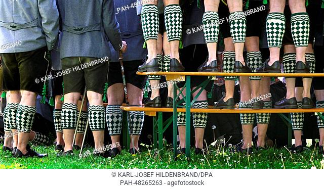 Musicians of the band Garmisch wearing traditional Bavarian costumes stand on beer benches and tables to take a group photo in the spa park of...