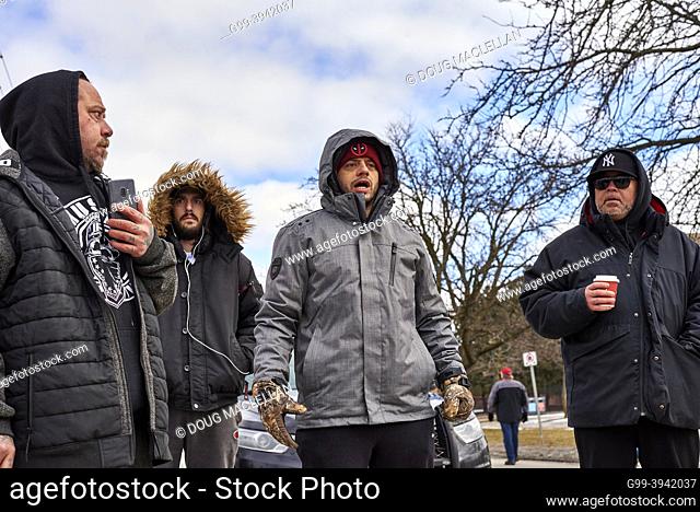 A man shouts out a list of grivances while three other men listen on 12 February 2022 at a police barrier on day six of the Freedom Convoy blockade of the...