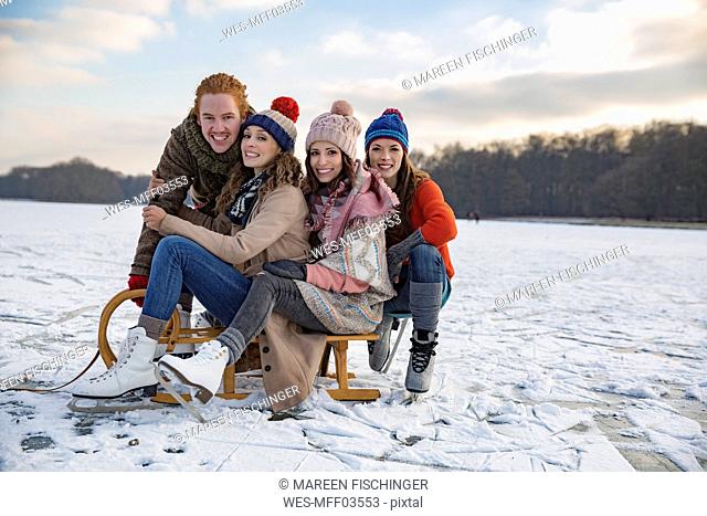 Friends having fun with sledge on frozen lake