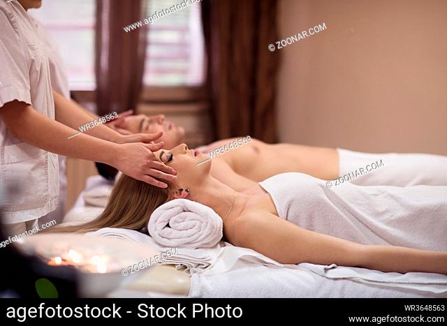 happy young beautiful couple enjoying head massage at the spa