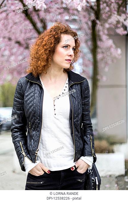 A woman with red, curly hair walking outdoors in springtime; North Vancouver, British Columbia, Canada