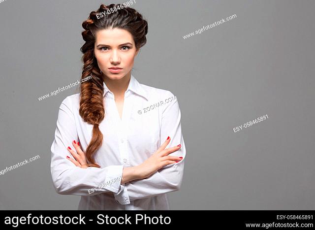 Portrait of beautiful woman with braids posing over grey background. Female lady with modern hairstyle in studio