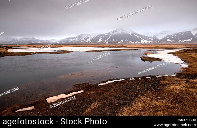 Typical Icelandic dramatic landscape with frozen lake and mountains covered in snow in Iceland