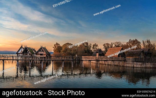 Old german shacks built over water on wooden pillars, on Bodensee lake, a pile structure, in Unteruhldingen, Germany, colorful sunset