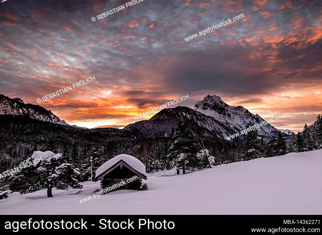 Haystack above Mittenwald at nightfall with sunset in winter. In the background the Wetterstein