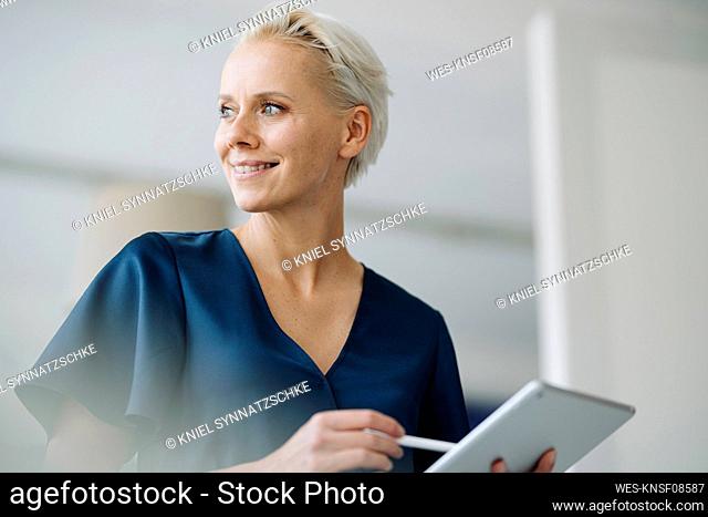 Close-up of thoughtful female entrepreneur holding digital tablet in office